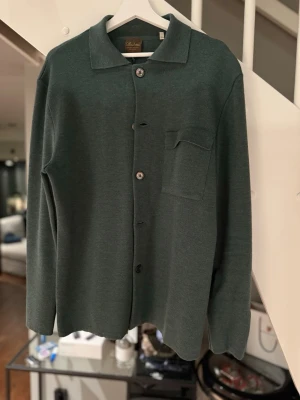 Grön stickad overshirt från stenströms - Stilren grön overshirt från stenströms med klassisk krage, bröstficka och knappar framtill. Overshirten har lång ärm och en rak passform, perfekt för en clean och enkel look. Ny pris 3999kr