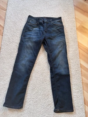 Mörkblå slim straight jeans Jack & Jones - Snygga mörkblå jeans från Jack & Jones i modellen Slim Straight. Klassisk femficksdesign, mjukt denimtyg för skön passform.