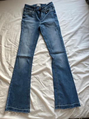 Blå bootcut jeans  - Säljer ett par blå bootcut jeans. Jeansen har klassisk femficksdesign, normalhög midja och är tillverkade i denim. Perfekta för dig som gillar en retroinspirerad look med utsvängda ben. Uppsprättade längst ner. 