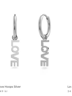 Silverörhängen med LOVE-hänge Edblad  - Snygga örhängen i silverfärg med små hoops och ett hänge där det står LOVE i blockbokstäver. Perfekta för att ge din look en cool och trendig touch. Tillverkade i metall med blank finish. Kostar  349 säljer för 269kr