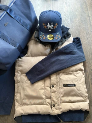 Beige väst från Canada goose - Jag säljer en vintage väst från Canada goose med två stora framfickor och svarta tryckknappar. Riktigt snygg vintage väst som passar när det är lite småkallt ute. Passar både tjejer och killar, västen har någon fläck som troligen går bort i tvätt (se bild 2). Västen är XS men passar också S.