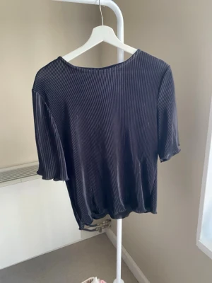 Svart ribbad topp med kort ärm - Säljer en svart ribbad topp med korta ärmar och rund hals. Toppen har en croppad passform och är tillverkad i ett mjukt, stretchigt material som känns skönt mot huden. Perfekt att styla med höga jeans eller kjol.