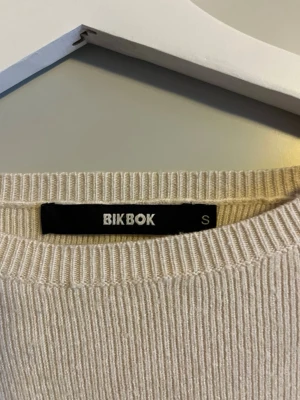 Beige ribbad tröja från BikBok - Snygg beige ribbstickad tröja från BikBok med rund halsringning och långa ärmar. Enkel och stilren modell som passar perfekt till jeans eller kjol. Mjuk och skön känsla, perfekt för lager-på-lager.