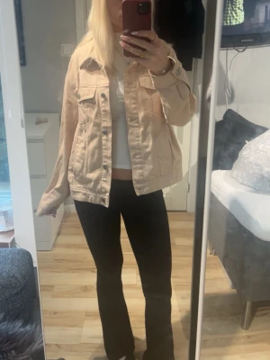 Beige jeansjacka med fickor - Säljer en snygg beige jeansjacka med klassisk krage och två bröstfickor med lock. Jackan har knäppning framtill och vid ärmslut, samt raka ärmar och en avslappnad passform.220 kr