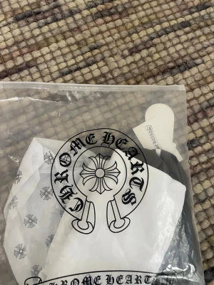 Svart Chrome Hearts t-shirt - Snygg svart t-shirt från Chrome Hearts med klassisk logga och detaljerade etiketter. Perfekt för dig som gillar streetwear och vill sticka ut med en exklusiv look. T-shirten har en stilren design och är tillverkad i mjuk bomull.