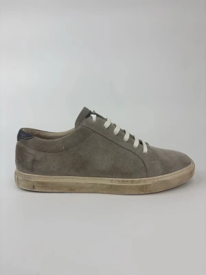 Grå Brunello Cucinelli mockasneakers med vita snören - Stilrena sneakers i grå mocka med vita snören och beige sula. Klassisk låg modell med enkel design som passar till det mesta. Ovandelen är i mjukt mockamaterial och sulan är i gummi. Perfekta för dig som gillar en clean och avslappnad look.