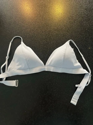 Ljusblå ribbad bikiniöverdel - Snygg ljusvit bikiniöverdel med triangelformade kupor och justerbara axelband. 