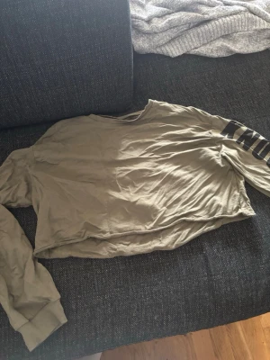 Croppad långärmad topp - Säljer en croppad långärmad topp med trycket 'KNOCK DOWN' i svart på ena ärmen. Toppen har en avslappnad passform. Lappen finns ej kvar men är strl L men jag skulle säga den passar som M. 