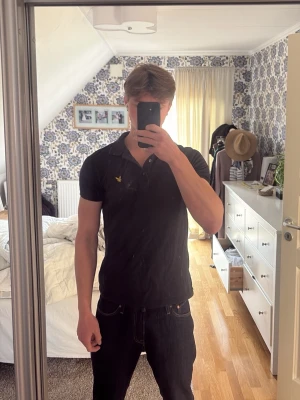 Mörkgrön pikétröja från Lyle & Scott - Klassisk skogsgrön pikétröja från Lyle & Scott med gul logga på bröstet. Tröjan har krage, korta ärmar och knappar vid halsen. Perfekt till jeans eller shorts för en clean och enkel stil. Jag är 184cm 75kg. Lite liten i storlek eventuellt 