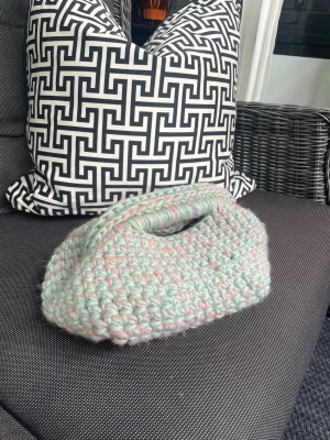 Handgjord virkad handväska i pastell - Superfin handväska som är virkad för hand i pastelliga toner av mintgrönt och ljusrosa. Väskan har en mjuk, chunky känsla och ett smidigt handtag upptill. Perfekt för dig som gillar unika accessoarer och vill sticka ut med en personlig stil. Garnen är av fårull och mohair