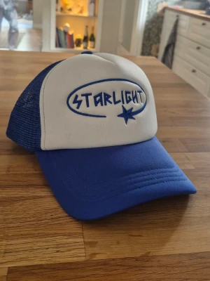 Blå och vit keps Starlight - Snygg truckerkeps i blått och vitt med broderad Starlight-logga framtill. Knappt använd
