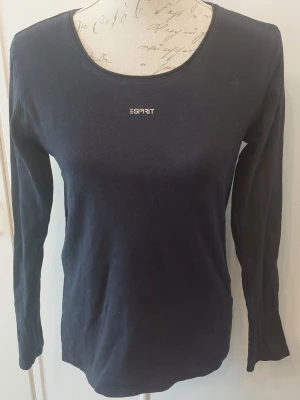Mörkblå långärmad topp från Esprit - En stilren mörkblå långärmad topp från Esprit med rund halsringning och diskret logga framtill. Tillverkad i mjuk bomull som känns skön mot huden. 