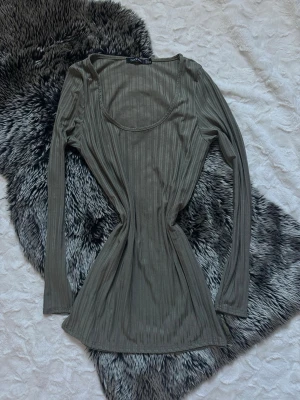 Ribbad långärmad topp från Boohoo - Snygg ribbad långärmad topp från Boohoo i en mörkgrön nyans. Toppen har rundad halsringning och är figurnära i modellen, perfekt att styla med jeans eller kjol. Materialet är mjukt och stretchigt för en bekväm känsla.