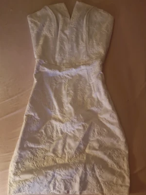 Vit spetsklänning med v-ringning - Elegant vit kortklänning med v-ringad hals och vackra spetsdetaljer. Klänningen är ärmlös och har en figurnära passform som framhäver siluetten. Perfekt för dig som vill ha en stilren och romantisk look. Ny utan prislapp. Priset kan diskuteras🫶🏼