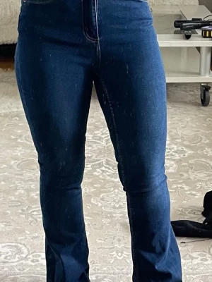Mörkblå bootcut jeans med hög midja - Snygga mörkblå jeans med bootcut och hög midja. Jeansen har klassisk femficksdesign och är tillverkade i stretchigt denimtyg för en bekväm passform. Perfekta för dig som gillar en tidlös och trendig look.
