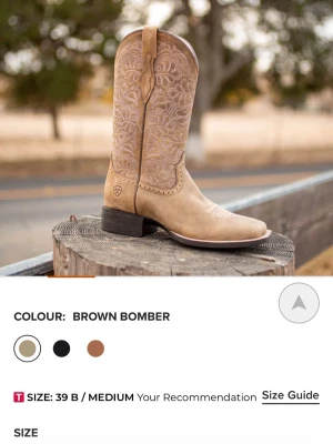 Ariat cowboy boots Brown Bomber - Snygga cowboy boots från Ariat i färgen Brown Bomber. Tillverkade i ljust brunt läder med rosa stygn,  robust sula och dragflikar upptill för enkel påtagning. Perfekta för stallet, ladugårn, eller bara ett par hållbara skor i allmänhet. Supersköna, säljer pga dom var för stora för mig