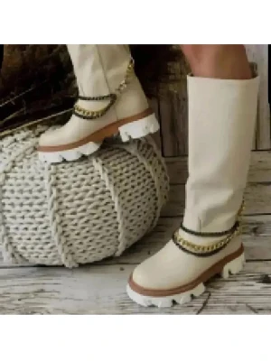 Beiga höga stövlar med kedjedetalj - Snygga höga stövlar i beige med chunky vit sula och dekorativa kedjor runt ankeln. Stövlarna har en modern, rak siluett och grov yttersula som ger en cool kontrast. Perfekta för dig som vill sticka ut med trendiga detaljer och stilren färg.avtagbar kedja. 