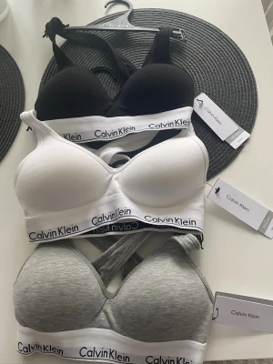 Calvin Klein bralette 3-pack - Säljer ett 3-pack bralettes från Calvin Klein i färgerna svart, vit och grå.  Helt nya , endast testat 1 gång. Perfekta för en sportig och avslappnad stil.650 kr för alla eller 250 kr styck 