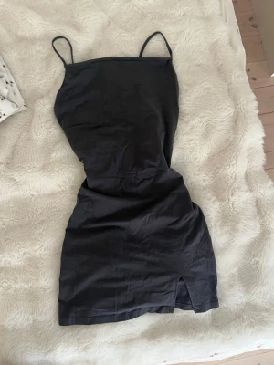 Kort Mörkgrå figurnära klänning med liten sido slits - Kort Mörkgrå figurnära klänning med liten sido slits  Bortklippta lappat men den är från hm, osäker på storlek men skulle säga s/ liten m . 