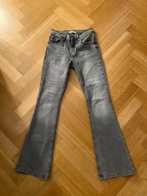 Gråa bootcut jeans med slitningar - Säljer ett par ljusgråa bootcut jeans med lågmidja från gina. Jeans är stretchiga med skönt matrial. 