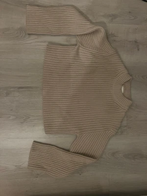 Beige ribbstickad tröja från H&M - Säljer en beige ribbstickad tröja från H&M med hög krage och långa ärmar. 