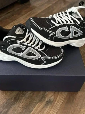 Svarta Dior b30 - Snygga svarta Dior sneakers med stora silvriga CD-loggor på sidorna och vita kontrastsömmar. Skorna har vita snören och en tjock vit sula som ger en sportig vibe. Materialet är en mix av mesh och syntet för både stil och komfort. Helt nya. Pris kan diskuteras!