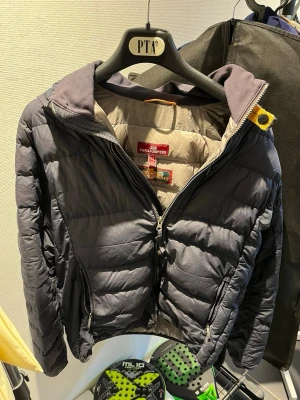 Mörkblå dunjacka från Parajumpers real  - Säljer en mörkblå dunjacka från Parajumpers i modellen Super Lightweight. Jackan har två dragkedjeförsedda fickor, quiltad design och en gul detalj vid kragen. Insidan är ljusgrå och materialet är lätt och smidigt, perfekt för kalla vinterdagar.