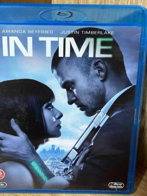 Blu-ray film In Time - Säljer Blu-ray-utgåvan av filmen In Time med Amanda Seyfried och Justin Timberlake. Omslaget är blått och har futuristiskt motiv med stad och digitala element. Filmen är en thriller från 2011 och har svensk text. Perfekt för filmkvällar.