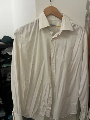 Vit skjorta från Valentino - Klassisk vit skjorta från Valentino med krage och knäppning framtill. Skjortan har lång ärm och är tillverkad i ett mjukt bomullstyg. Perfekt för en clean och stilren look.