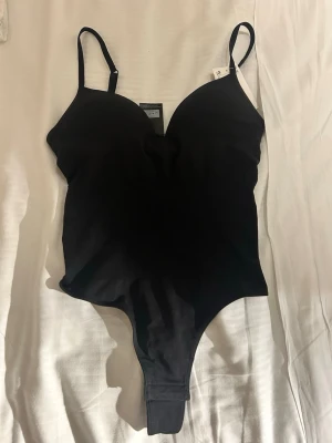 Svart body från H&M - Snygg svart body från H&M med justerbara axelband och vadderade kupor.med prislapp kvar. Pris kan diskuteras!!💕