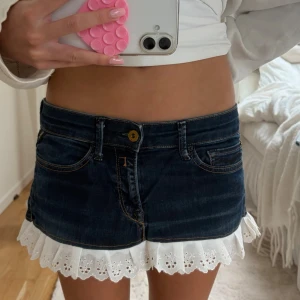 Jättefin jeanskjol - Supersöt kort jeanskjol med vit spetsvolang längst ner och spetsdetaljer på bakfickorna😇😇Köpte den på vinted, säljer för att den inte kommit till användning💕💕från replay men ganska säker på att de har gjorts om från jeans till en kjol! Jättefin till sommaren💖💖
