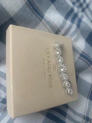 Glittrig hårklämma från Lily and Rose - Säljer en elegant hårklämma från Lily and Rose med stora, runda, gnistrande kristaller i silverfärgad metall. Perfekt accessoar för att ge håret extra bling och stil. Klämman har en klassisk form och känns riktigt lyxig.