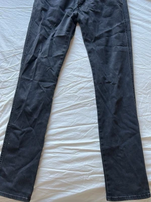 Svarta raka Replay jeans - Säljer ett par svarta jeans med rak passform och klassisk femficksdesign. Jeansen har normal midja och är tillverkade i ett mjukt denimtyg som känns bekvämt. Perfekta för dig som gillar en enkel och stilren look.