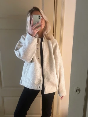 Beige teddy cardiganjacka - Mysig och oversized beige cardiganjacka med knappar framtill och två sidfickor. Jackan har en fluffig teddystruktur och är perfekt att slänga på sig över en t-shirt eller hoodie. Passar dig som gillar en avslappnad och trendig stil.