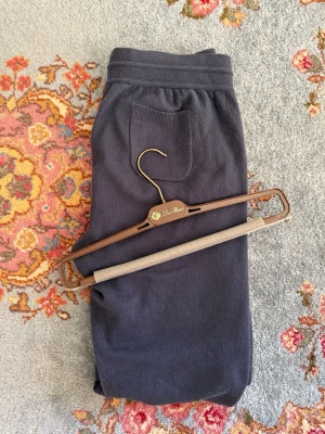 Loro Piana Baby Cashmere Merano - Exklusiva mörkblå mjukisbyxor från Loro Piana i 100% baby cashmere. Byxorna har en bakficka och resår i midjan för extra komfort. Perfekta för dig som vill ha något riktigt mjukt och lyxigt i garderoben. Retail 2100€, dammodell men passar även herrstorlek 48.