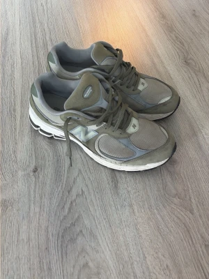 Gröna New Balance 2002r - Snygga New Balance 2002r sneakers i grönt med mesh och mockadetaljer. Skorna har klassisk N-logga på sidan, vadderad plös och häl samt slitstark vit sula med svarta detaljer. Perfekta för en sportig och trendig look. Använda fåtal gånger så bra skick, köpta för några mån sedan.