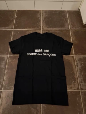 Commes des garcons t shirt  - Riktigt fet och eftertraktad t-shirt med commes des garcons loggan i storlek S. Väldigt bra skick!  Obs: Jag är lite osäker på äktheten då lappen i nacken saknas, därför säljs den billigare (499 kr, nypris ca 3000 kr).  längd cirka 65cm, bredd cirka 44cm. Tveka inte att höra av dig vid frågor eller funderingar!