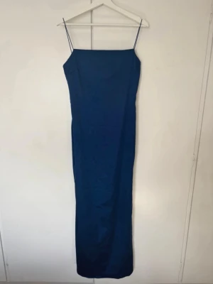 Marinblå balklänning från Nelly - En jättefin marinblå satin balklänning från Nelly som är helt ny med prislapp kvar. Den är i storlek 38.