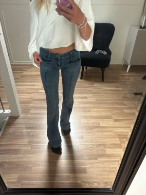Blå bootcut jeans low waist med fickdetaljer - Snygga blå bootcut jeans med markerade sömmar och coola fickdetaljer fram och bak. Från Nelly i storlek 34 nypris 699kr