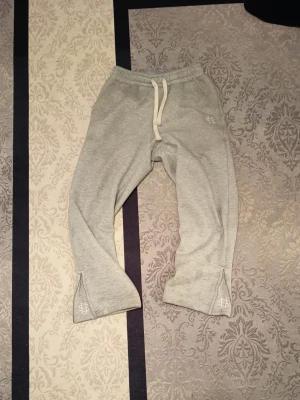 Grå mjukisbyxor från suvene  - Snygga grå mjukisbyxor från SikSilk med broderad logga vid benslut och dragsko i midjan. Byxorna har en relaxed fit och är tillverkade i mjukt material som passar perfekt för chill dagar. Stilsäkra detaljer med slits vid benslut.