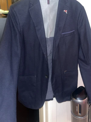 Mörkblå kavaj från Zara  - Snygg mörkblå kavaj från Zara med klassisk passform, två framfickor och bröstficka med diskret logga. Kavajen har enkla knappar och är tillverkad i ett mjukt tyg som ger en stilren look. Perfekt för dig som vill ha en tidlös och trendig stil. Storlek xs passar s