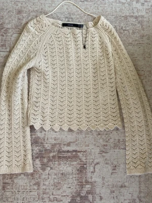 Beige stickad tröja från Vero Moda - Säljer en beige stickad tröja från Vero Moda med lång ärm och ett snyggt hålmönster. Tröjan har rund halsringning och vågig kant nedtill för en extra detalj. Perfekt att styla med jeans eller kjol för en trendig look. Den är för liten och därför säljs den💕 nästan aldrig använt