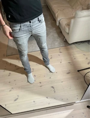 Jack&Jones jeans  - W30 L32. Säljer ett par ljusgrå slim fit jeans med klassisk femficksdesign och låg midja. Jeansen har en snygg tvättad look och smal passform som sitter tajt längs benen. Perfekta för en modern och stilren outfit.