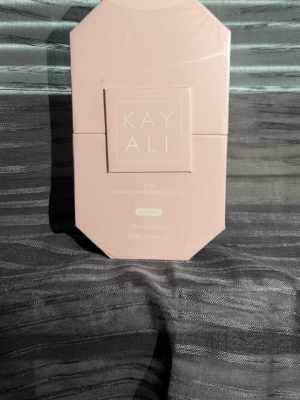 Kayali Yum Eau De Parfum 100ml - Kayali Yum Eau De Parfum Intense kommer i en lyxig, ljusrosa, åttakantig förpackning. Doften är Boujee Marshmallow och flaskan rymmer 100 ml. Perfekt för dig som gillar söta och unika parfymer med elegant design.