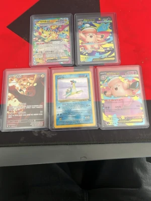 Pokémon samlarkort i plastfickor - Fem Pokémon samlarkort i genomskinliga plastfickor. Motiven inkluderar Pikachu, Lapras och Clefairy med färgglada och glansiga illustrationer. Kortens text är på både engelska och koreanska. Perfekt för dig som gillar att samla eller spela Pokémonkort.