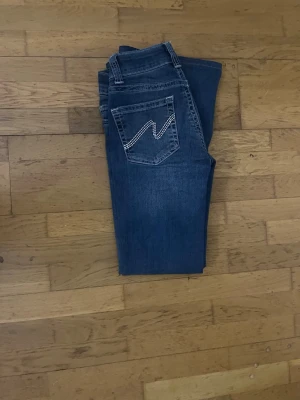 Blå jeans från Nelly med broderad ficka - Snygga blå jeans från Nelly nästan som nya, storlek 32 o är uppsydda noggrant o passar nån runt 160