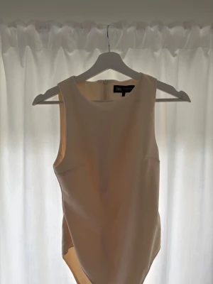 Beige body från Zara - Säljer en stilren beige body från Zara med rund halsringning och ärmlös design. Materialet är slätt och stretchigt, vilket ger en snygg passform. Perfekt att matcha med jeans eller kjol för en clean look.