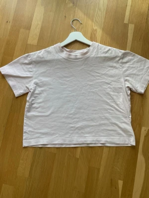 Ljusrosa croppad t-shirt - En basic ljusrosa t-shirt med croppad passform och rund halsringning. T-shirten är kortärmad och tillverkad i mjuk bomull, perfekt för en avslappnad och trendig look