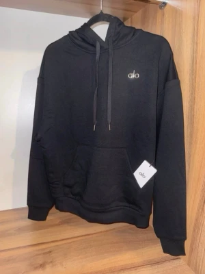 Svart hoodie från Alo Yoga S (36) - Snygg svart hoodie från Alo med huva, dragsko och en stor magficka framtill