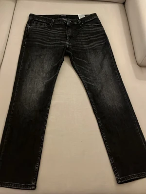 Svarta raka jeans med tvättade detaljer - Säljer ett par svarta jeans med raka ben och snygga tvättade detaljer. Jeansen har klassisk femficksdesign, normal midja och kontrastsömmar. Materialet är denim i bomull och de har en avslappnad passform som funkar till många stilar.